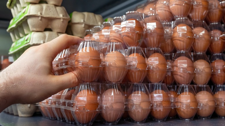 Hand grabbing brown eggs plastic cartons