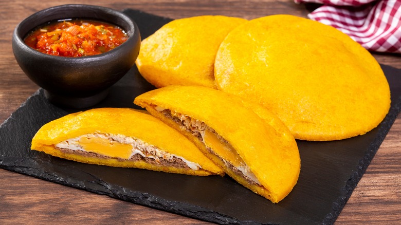 Arepas on a plate with a bowl of salsa