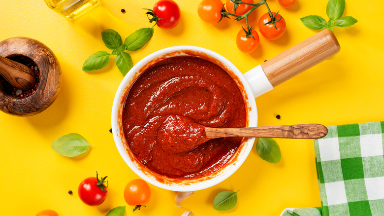 Pot of red sauce on yellow background
