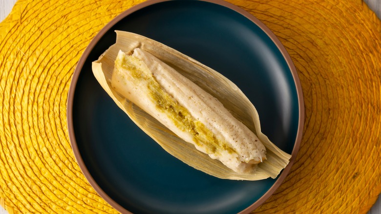 An unwrapped tamale on a black plate