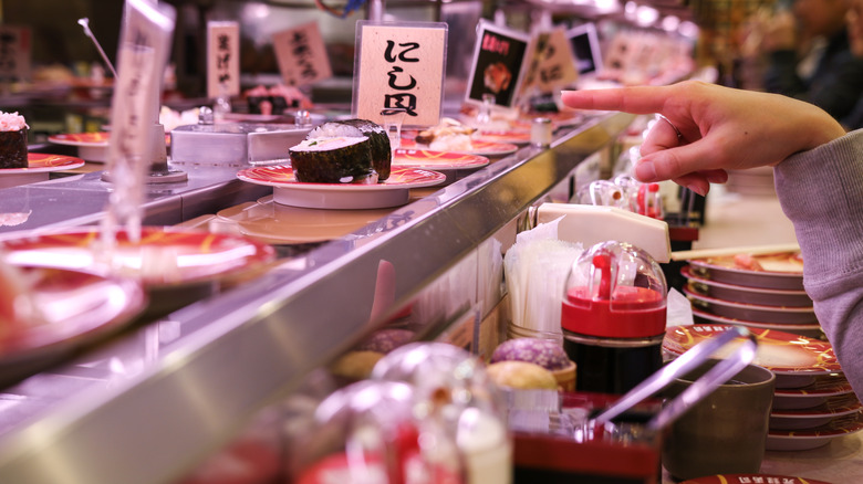 Customer pointing at dish in conveyor belt 