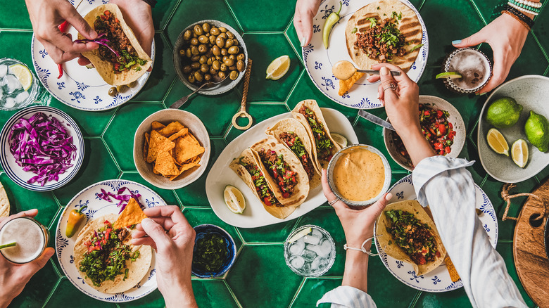 People sharing tacos on green table