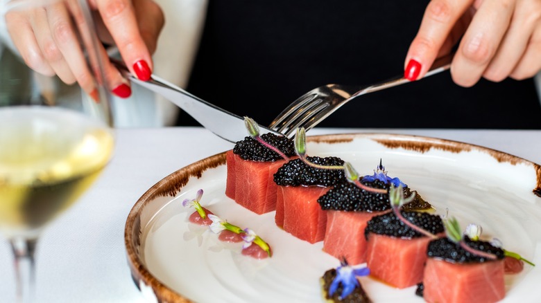 person's hands eating tuna with caviar