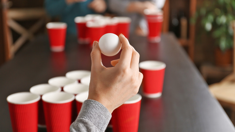 hand with ball at beer pong table