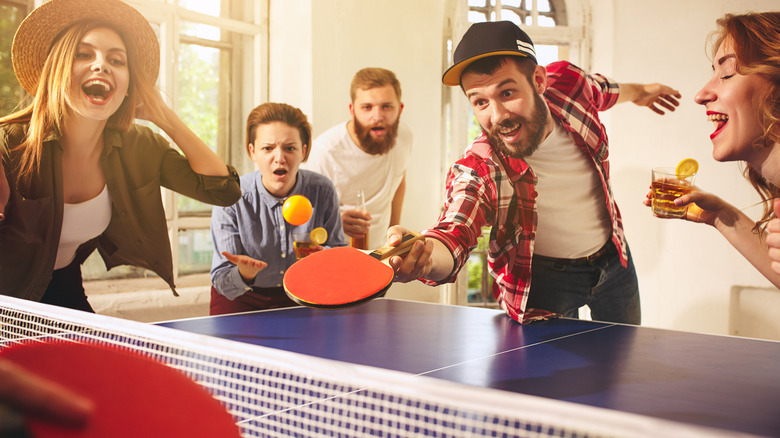 man leaning over ping pong table 