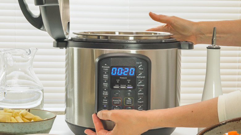 Woman pressing button on pressure cooker