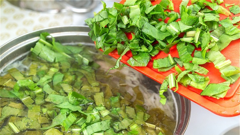 Chopped lettuce added to soup pot