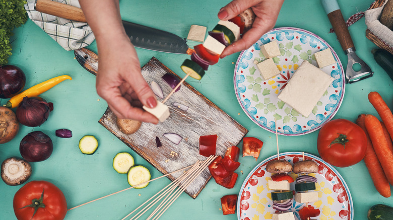 Preparing tofu and vegetable skewers for grilling.