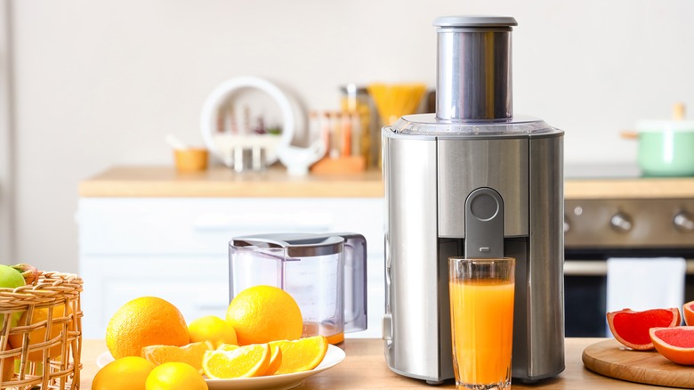 A glass of orange juice in front of a juicer