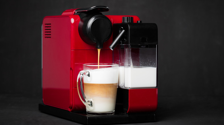 Nespresso machine pouring a cup of coffee with milk wand