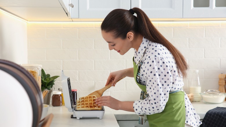 Woman in a kitchen making a waffle