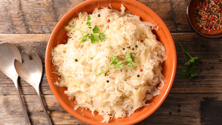 Sauerkraut in a brown bowl with herbs and spices