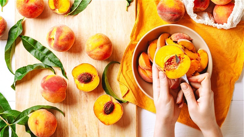 Hand cutting peaches over bowl 