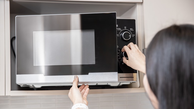 Woman setting microwave timer