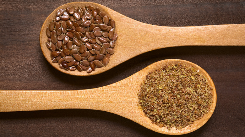 Whole and ground flaxseeds in wooden spoons