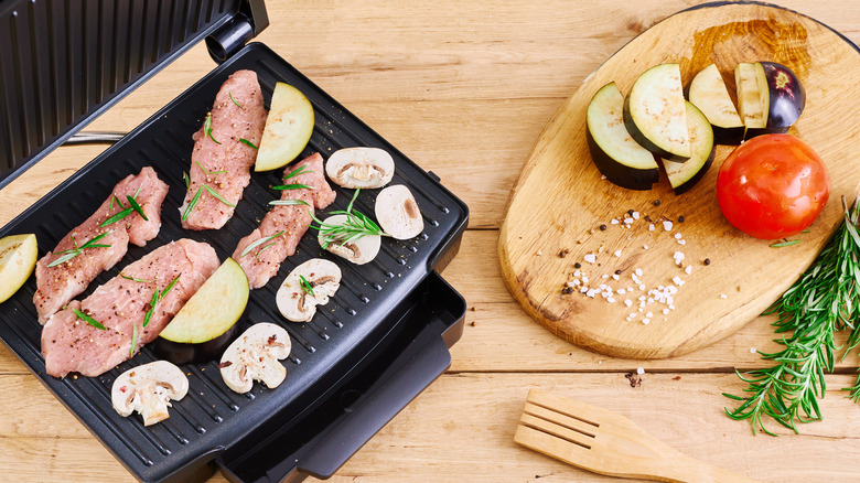 meat and mushrooms being cooked on a panini press