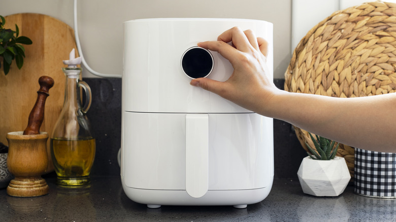 Person adjusting the temperature on an air fryer