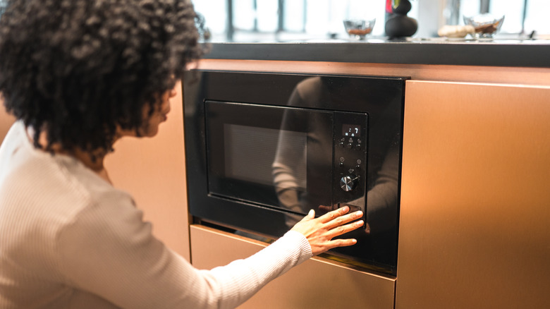 woman using microwave in a sleek modern kitchen