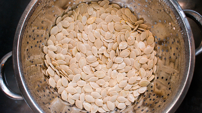 rinsing pumpkin seeds in a colander