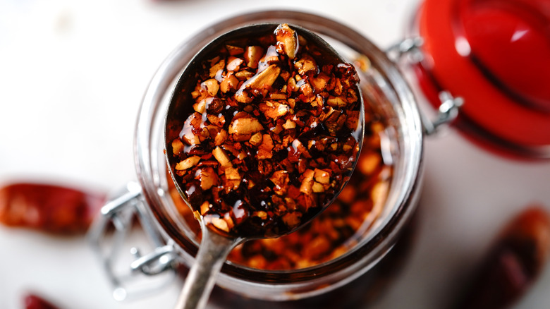 Spoonful chili crisp above jar 