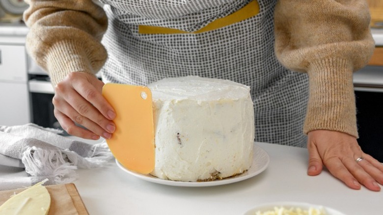 woman applying frosting to cake