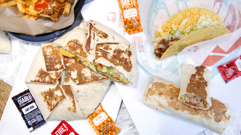 unwrapped taco bell items surrounded by sauce packets