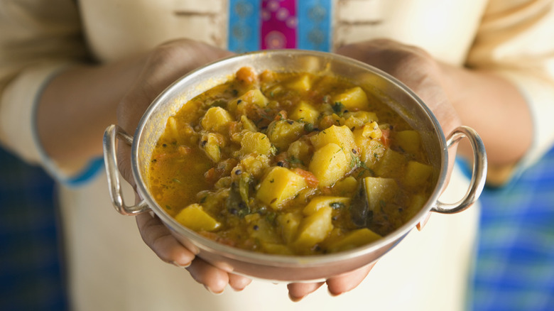 A person holds a bowl of potato soup