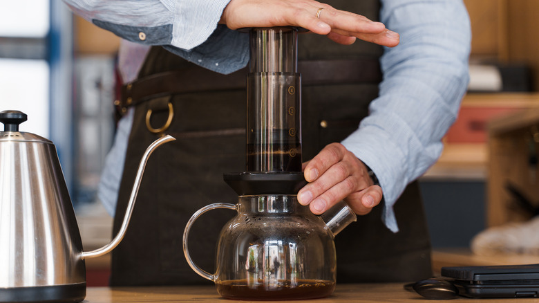 A person presses down on an AeroPress