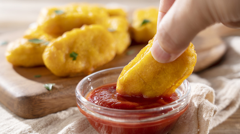 Chicken nuggets dipped in ketchup