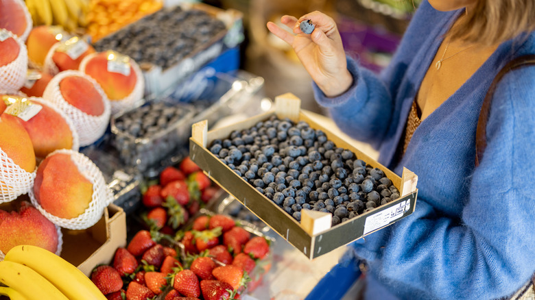 woman examining blueberries at market