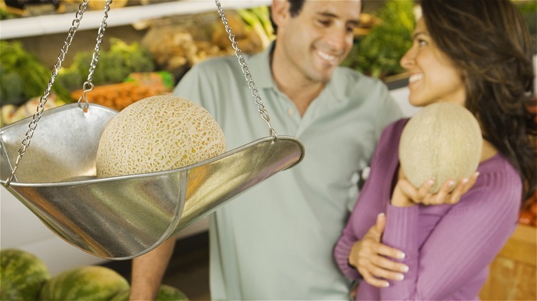 couple holding cantaloupe at supermarket