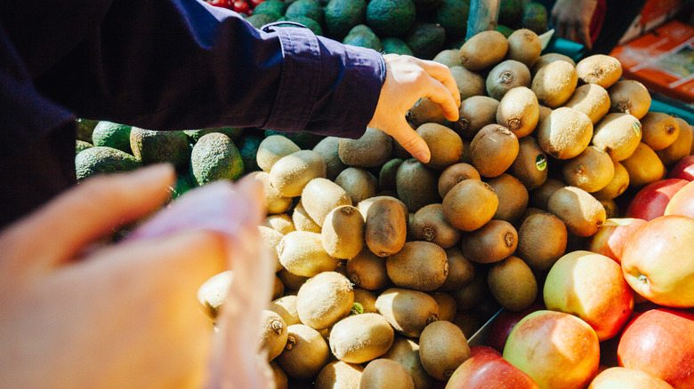 shopper picking out kiwi