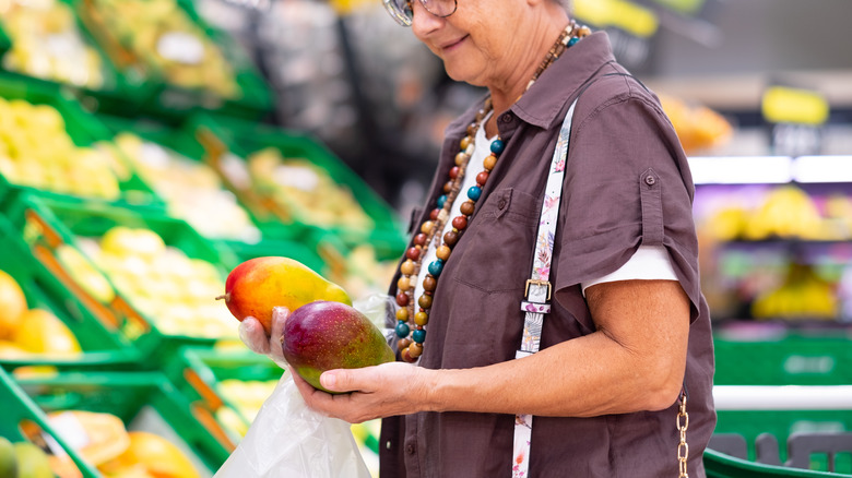 shopper comparing two mangoes