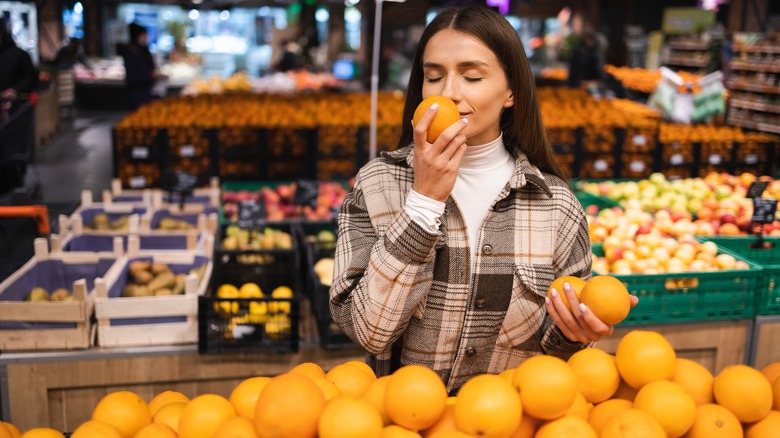 woman smelling orange in market