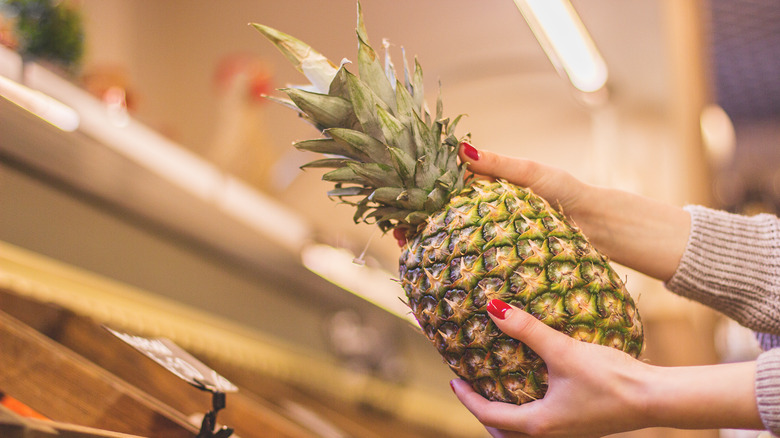 hands holding pineapple at market