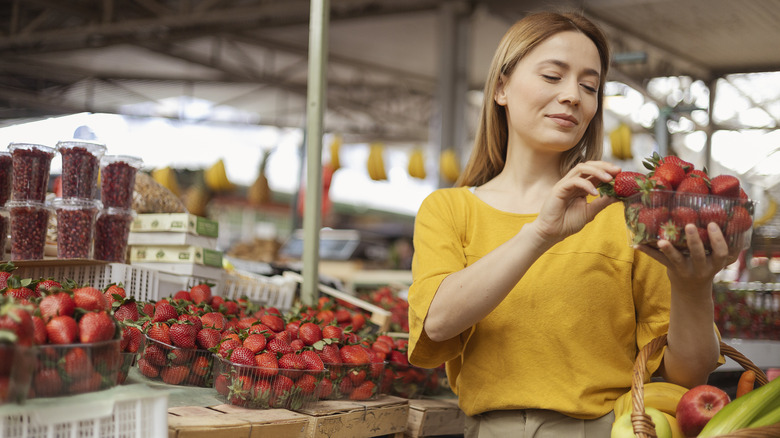 woman picking out strawberries at market