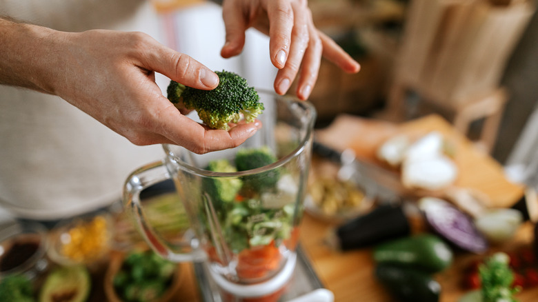 Man putting broccoli in blender