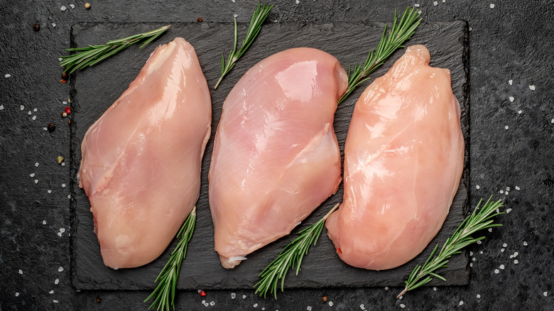 three raw chicken breasts placed on platter