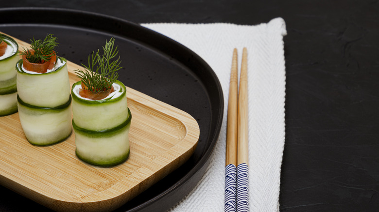 cucumber sushi rolls on plate with chopsticks