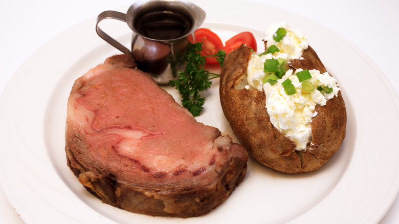 Prime rib and baked potato on a plate