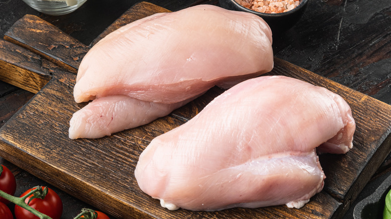 two chicken breasts on wooden board