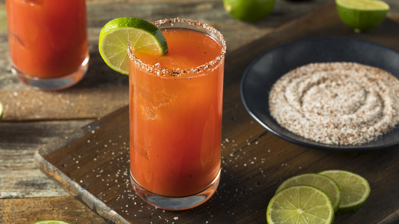 Michelada with a chili salt rim and plate of salt beside it.