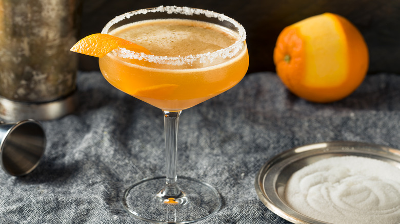 Sidecar cocktail with sugar rim next to plate of sugar