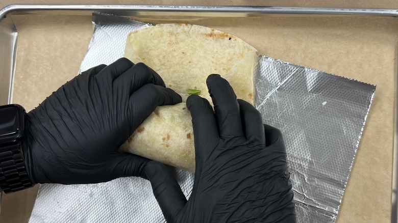 gloved hands rolling a burrito