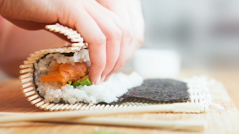 Hands rolling sushi