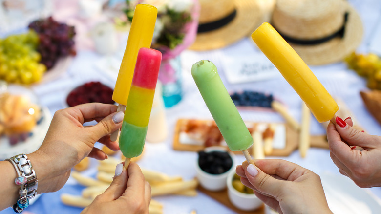 hands holding popsicles at picnic