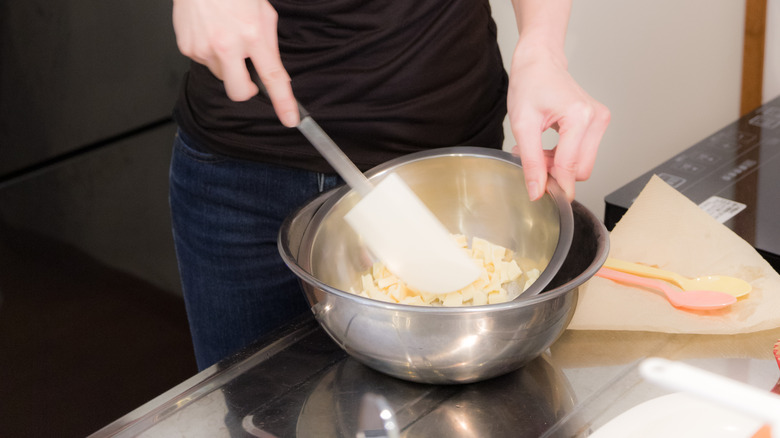 A girl mixing a bowl of white chocolate with a spatula