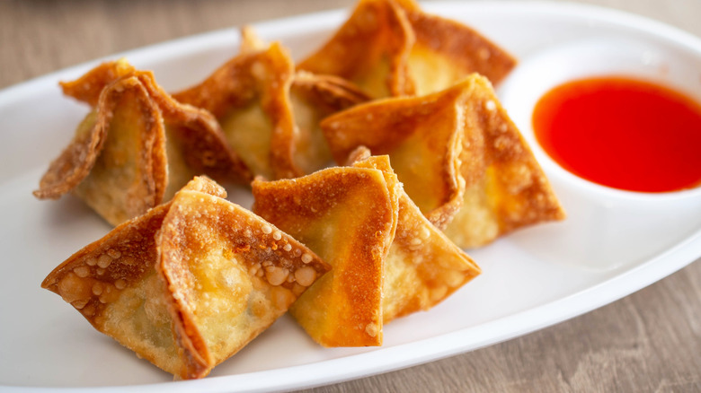 crab rangoon on a plate with dipping sauce