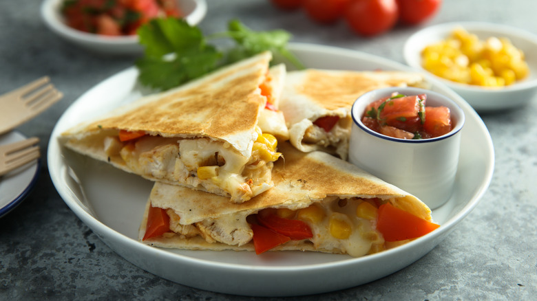 Veggie quesadilla on white plate with bowl of salsa