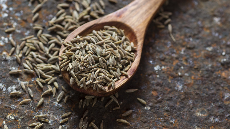 cumin seeds overflowing a wooden spoon